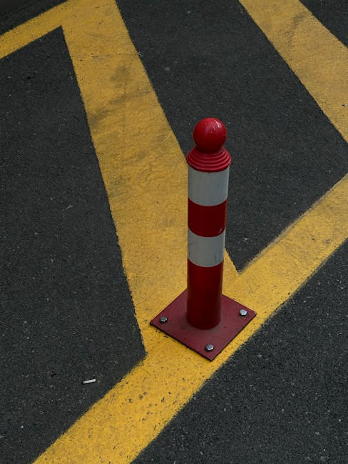 pexels-photo-17406219-17406219 Vertical red bollard on asphalt with yellow striped lines, urban traffic safety.